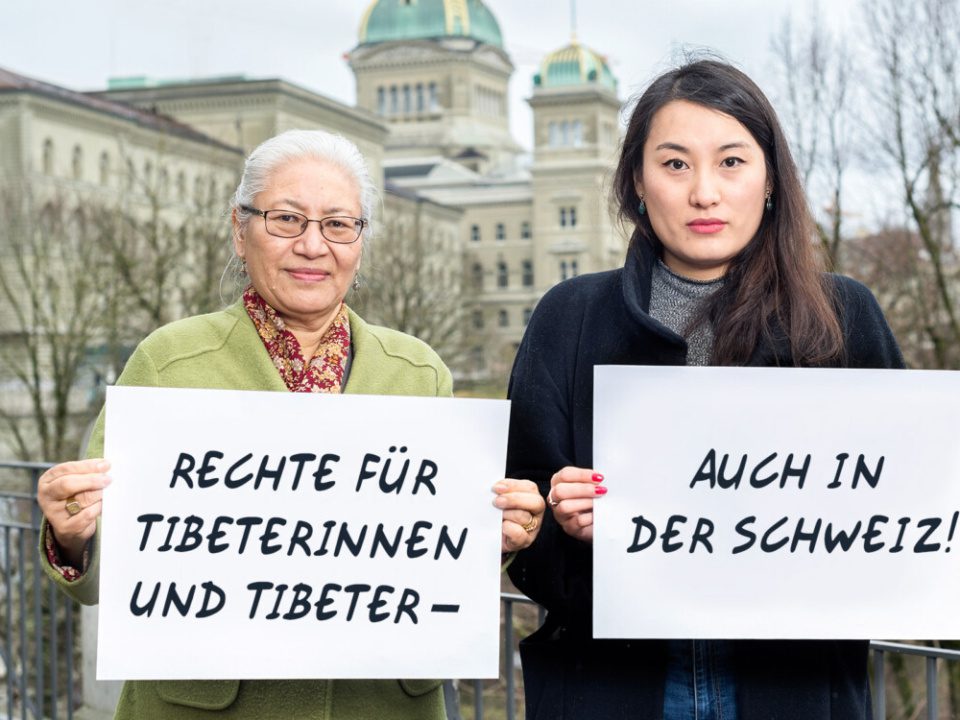 Zwei tibetische Aktivistinnen halten vor dem Bundeshaus ein Schild.